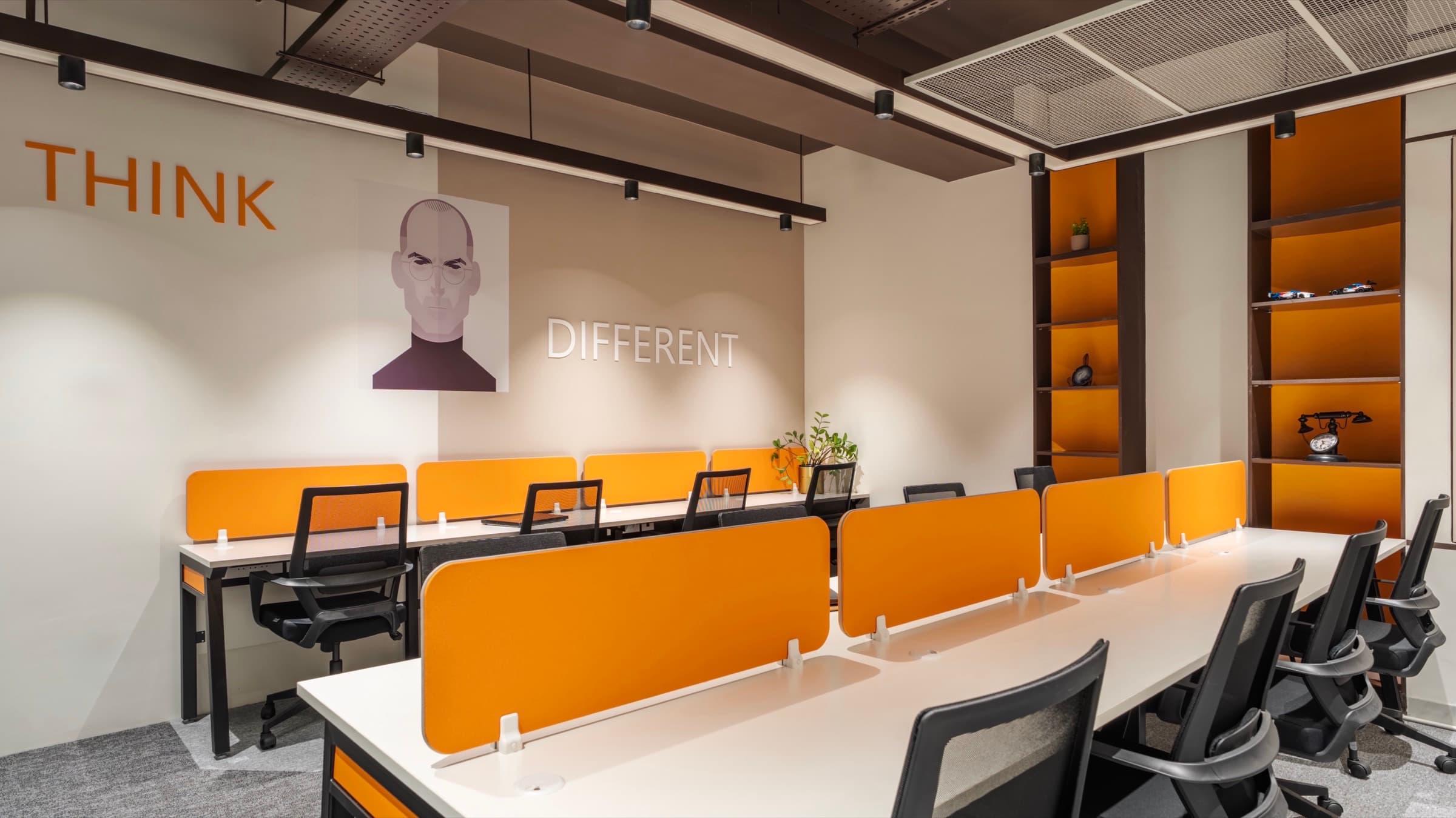 12 seater private office with Think Different mural, orange desk dividers and display shelving at Fliqzo Coimbatore