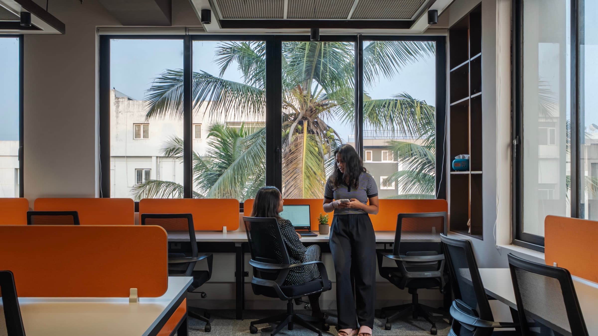 Team members talking beside palm-view windows in the 16 seater private office at Fliqzo Coimbatore