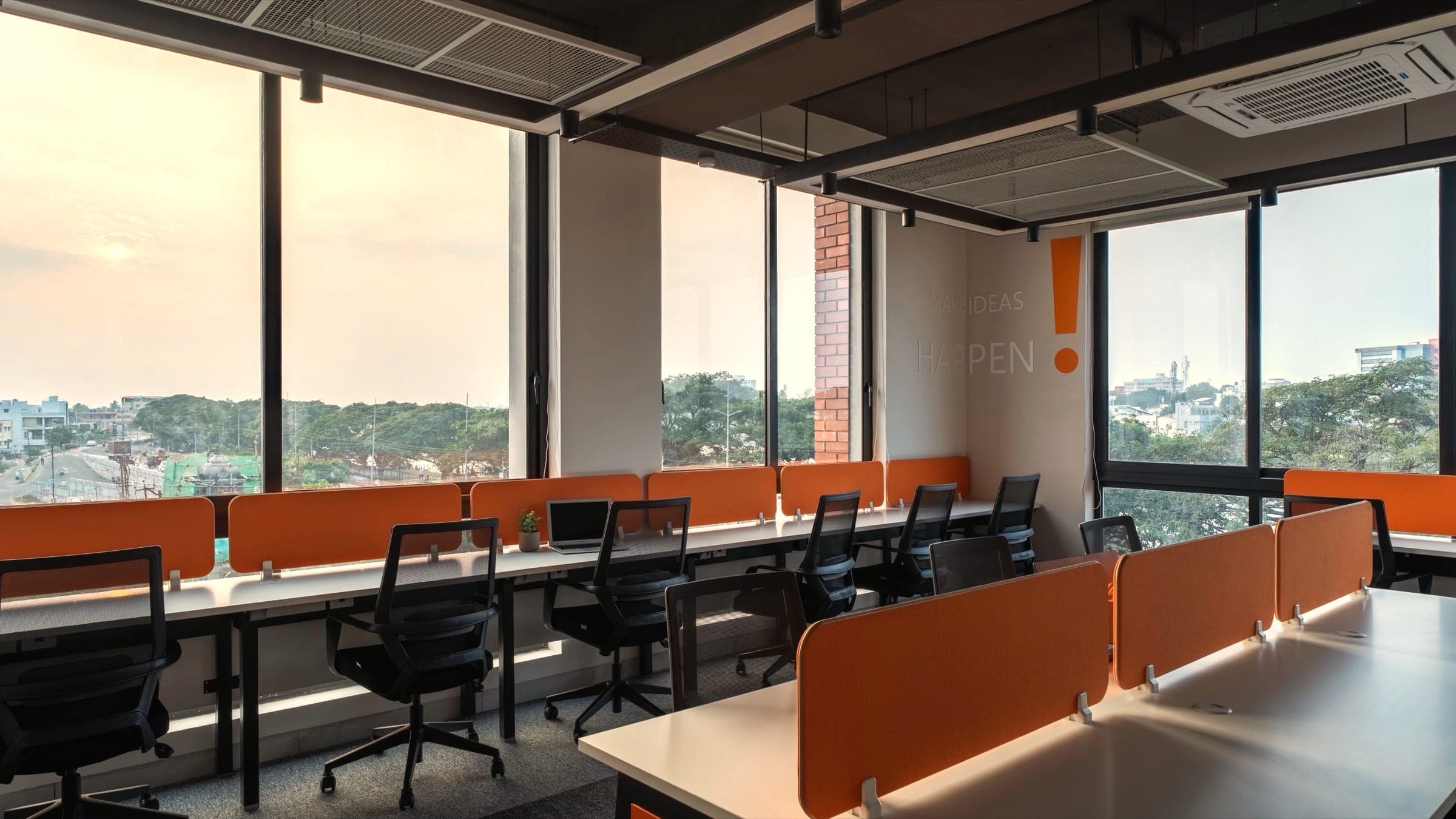 Golden-hour view across the 16 seater lake view private office at Fliqzo Coimbatore — Make Ideas Happen wall, wrap-around windows over the treeline