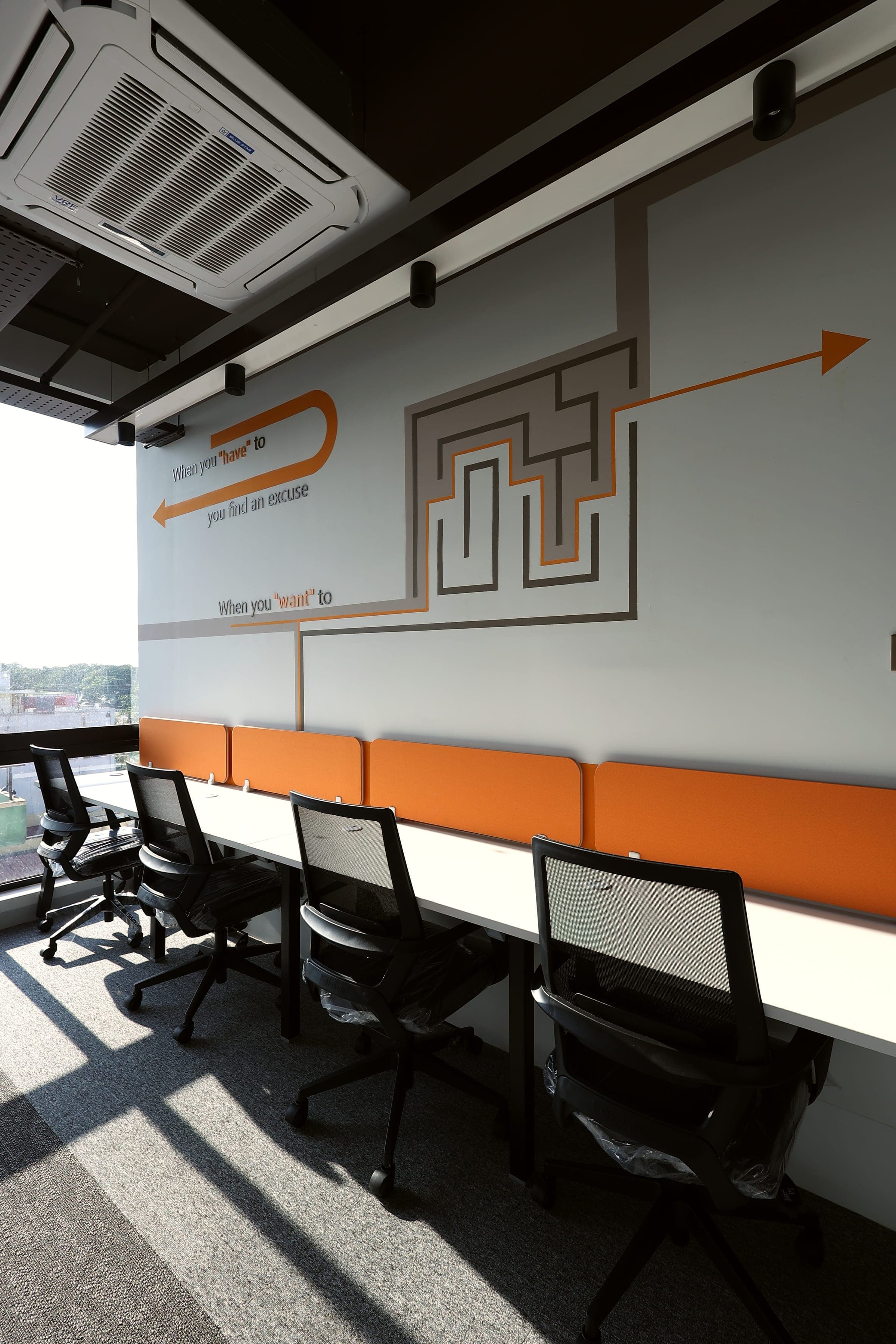 Four desks facing the When You Want To maze mural in the sunlit 4 seater private office at Fliqzo Coimbatore