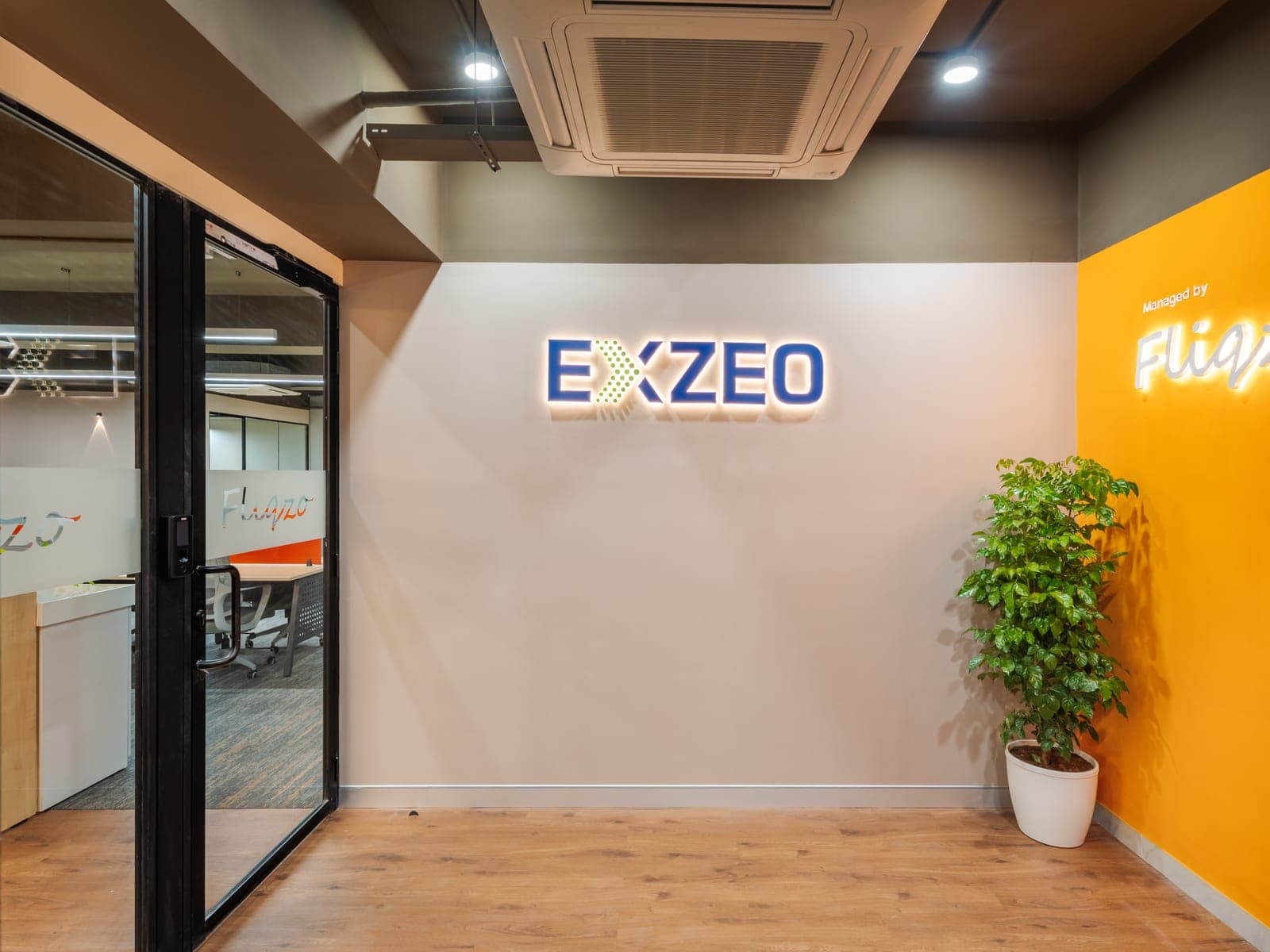 Exzeo logo and Managed by Fliqzo neon sign at the entrance of the 50 seater managed office in Coimbatore