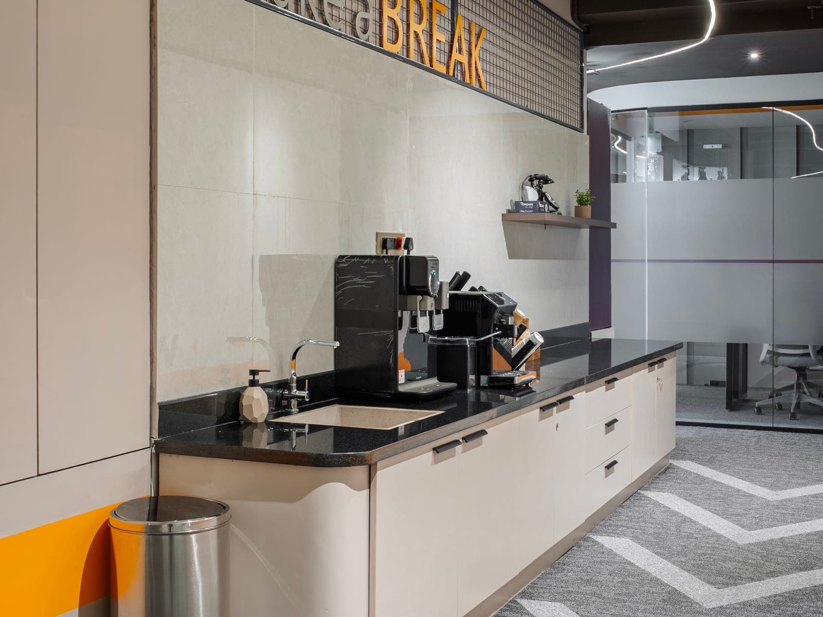 Take a Break pantry counter with barista coffee machines beside the glass meeting pod at Fliqzo Coimbatore