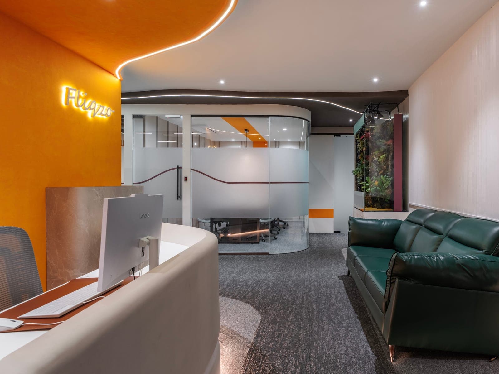 Reception lounge with green leather sofa and living paludarium beside the Fliqzo front desk, Coimbatore
